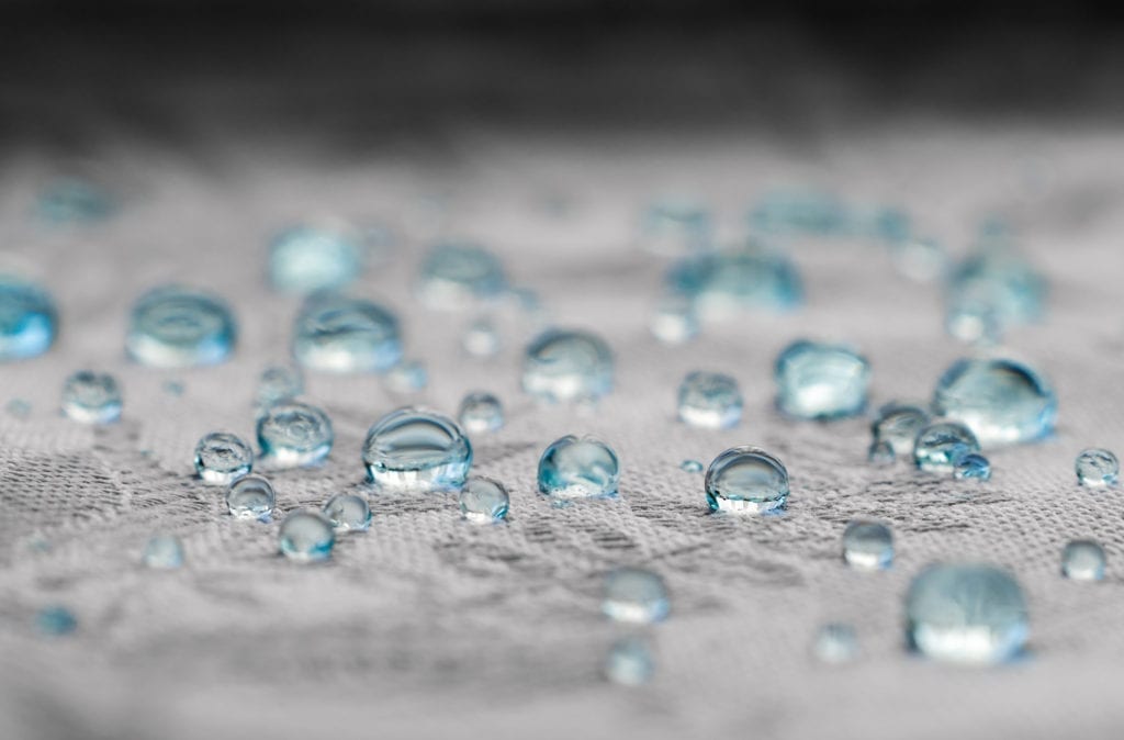 Blue water drops in macro view on textile fabric fibers