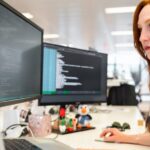 Female software engineer codes at computer