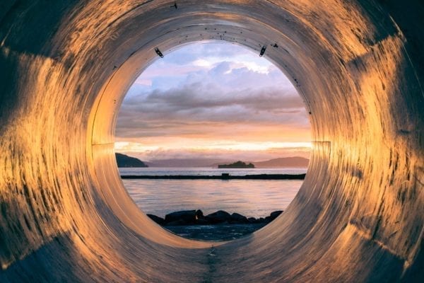 looking through pipeline at ocean with rocky shore