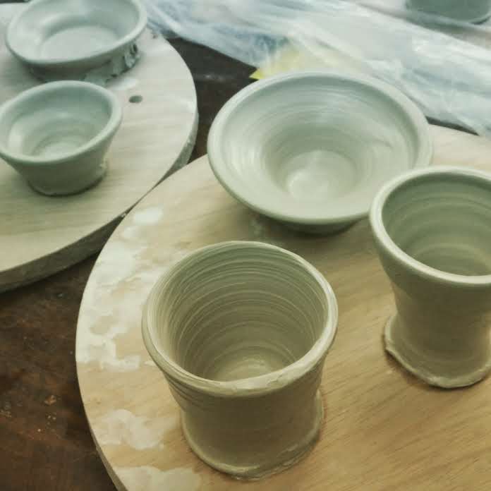 Clay mugs and bowls on two circular pieces of wood
