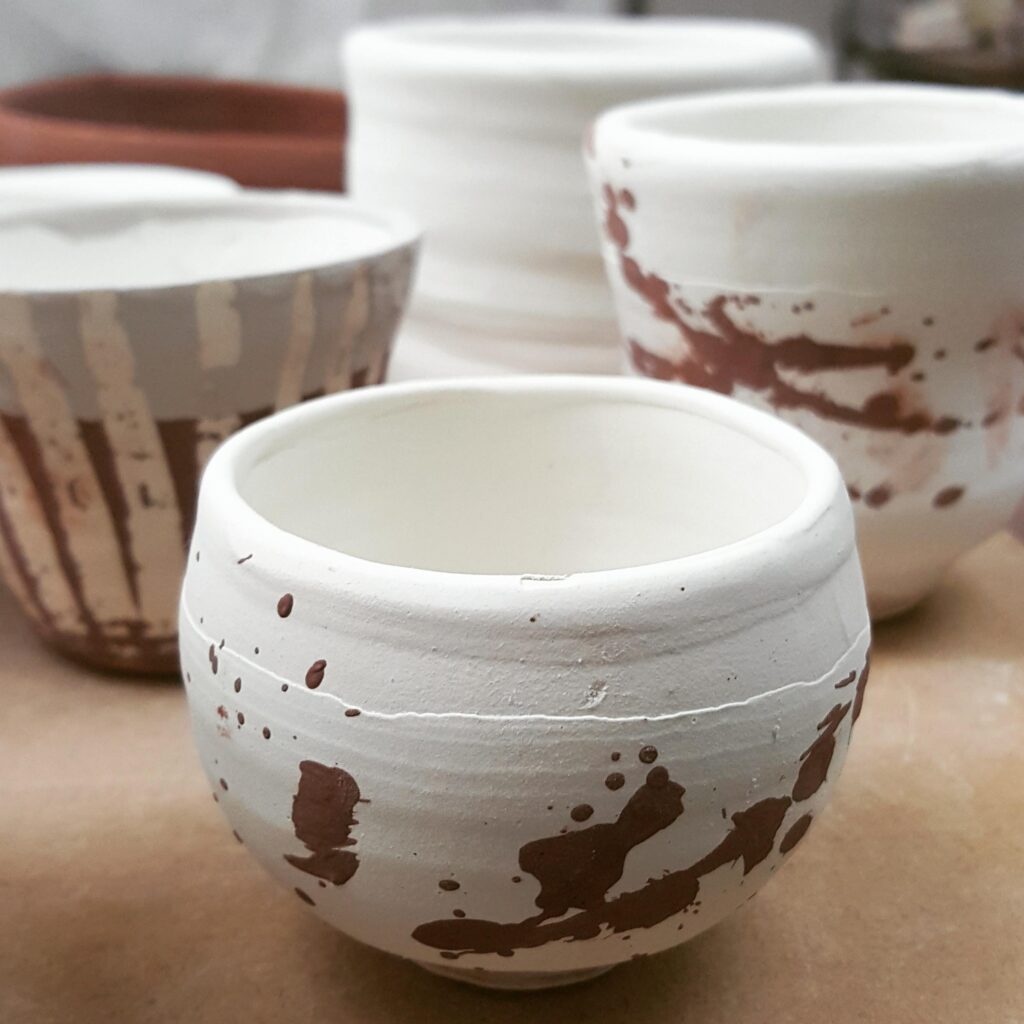 Clay bowls painted white with streaks and splashes of brown